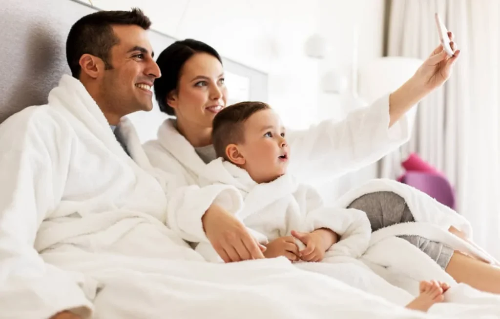 family taking selfie in hotel bed