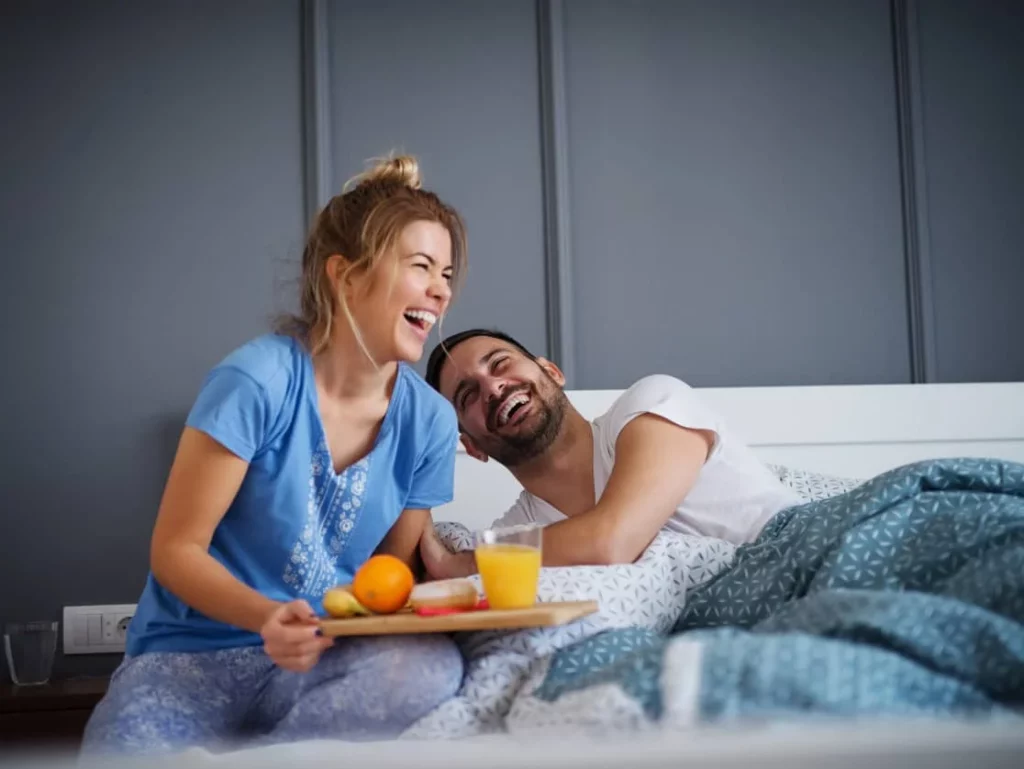 couple laughing in breakfast in bed