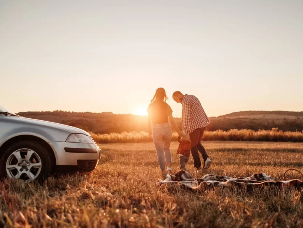 mother and father holding kids hand in field during sunset